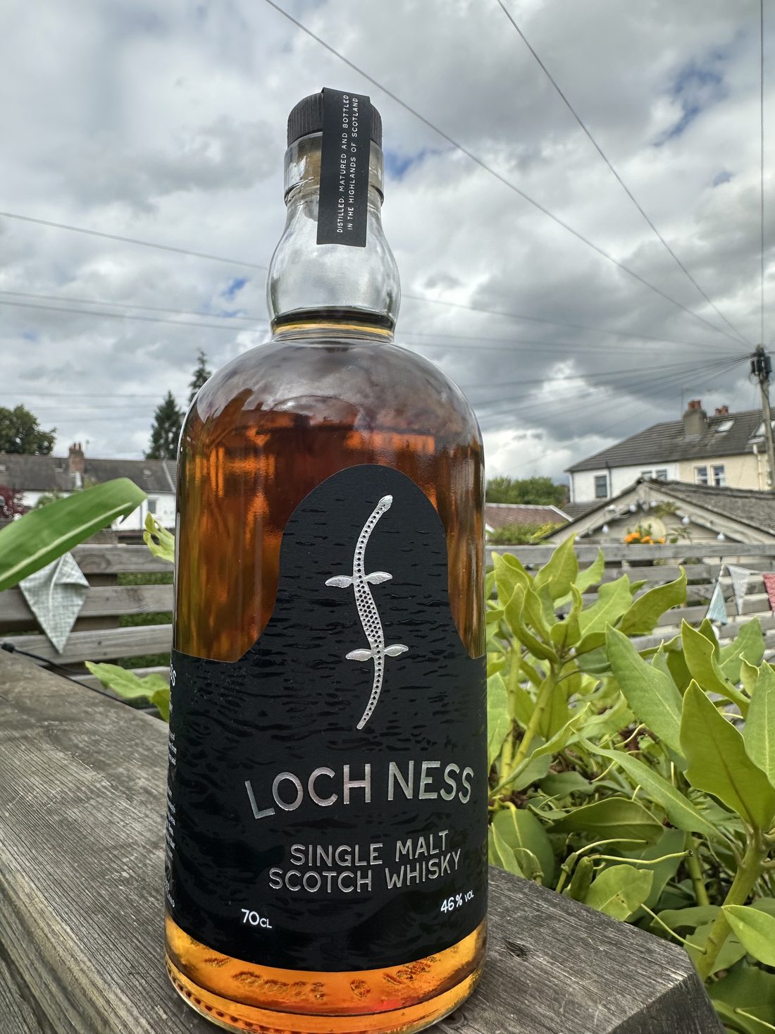 Loch Ness Single Malt Scotch Whisky bottle beside the Loch